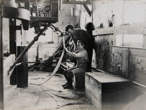 Young Boy in Factory with Man Working with String or Rope